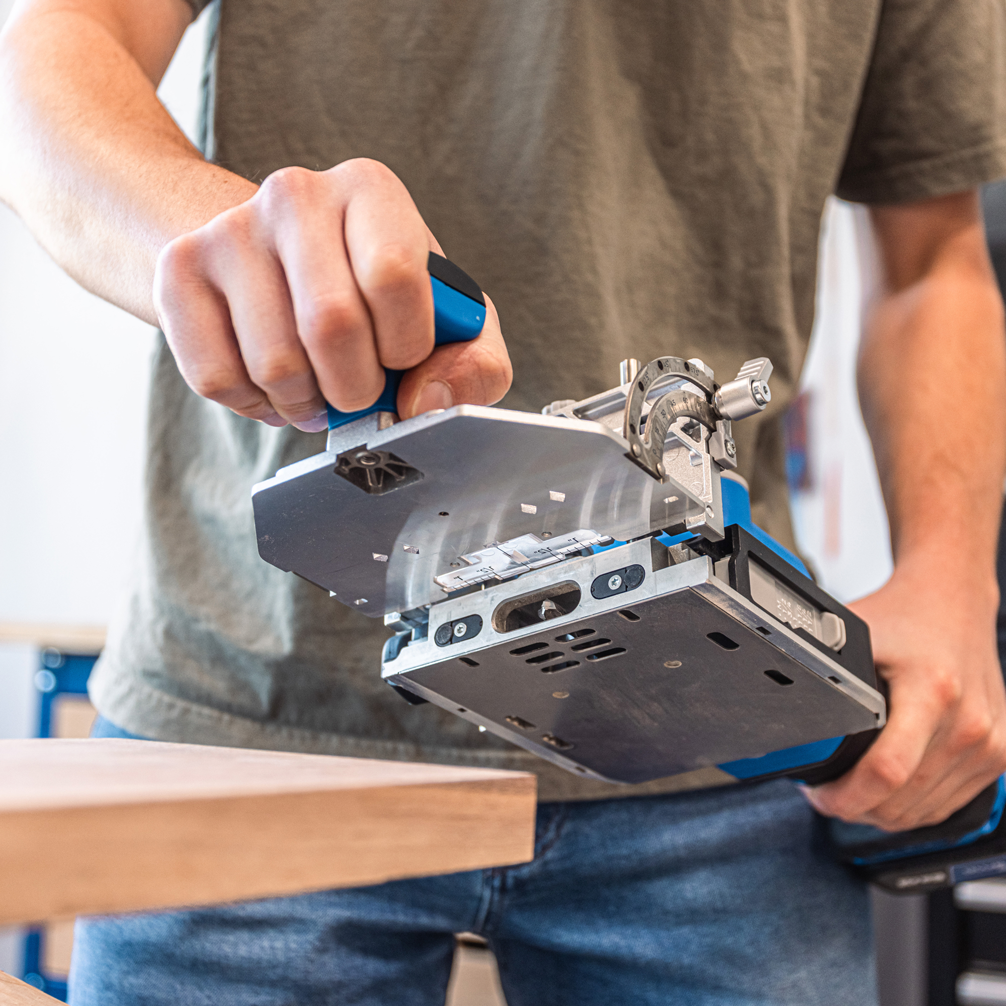 A man is lifting his Kreg Edge loose tenon joiner onto a wooden surface to drill some mortises
