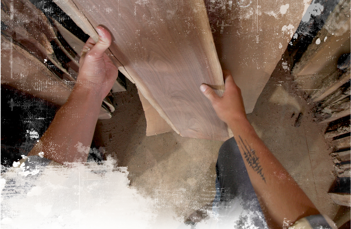 A man's hands are shown selecting a piece of lumber from a lumber rack. 