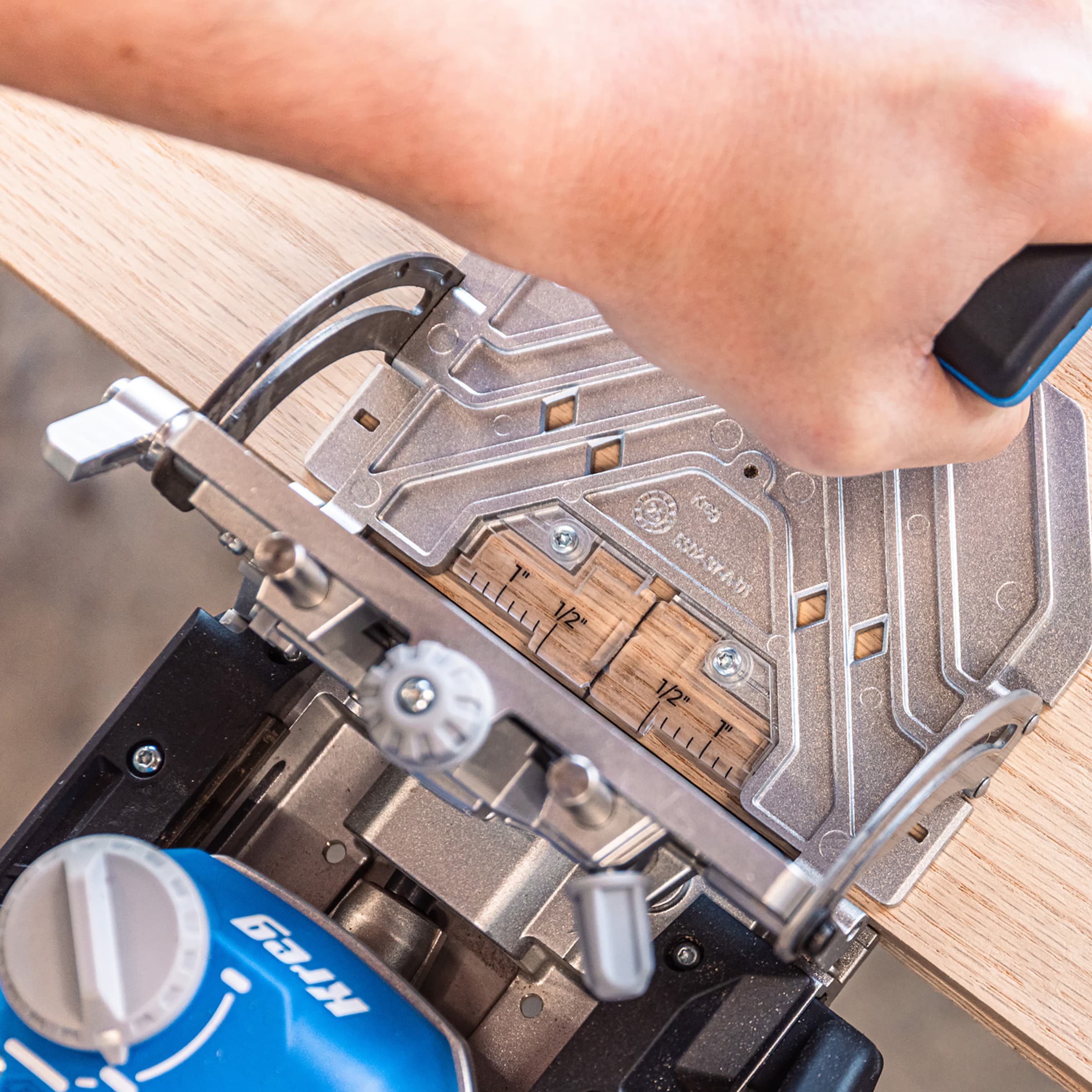 A hand is grasping the Kreg Edge as a mortise is being drilled into plywood.