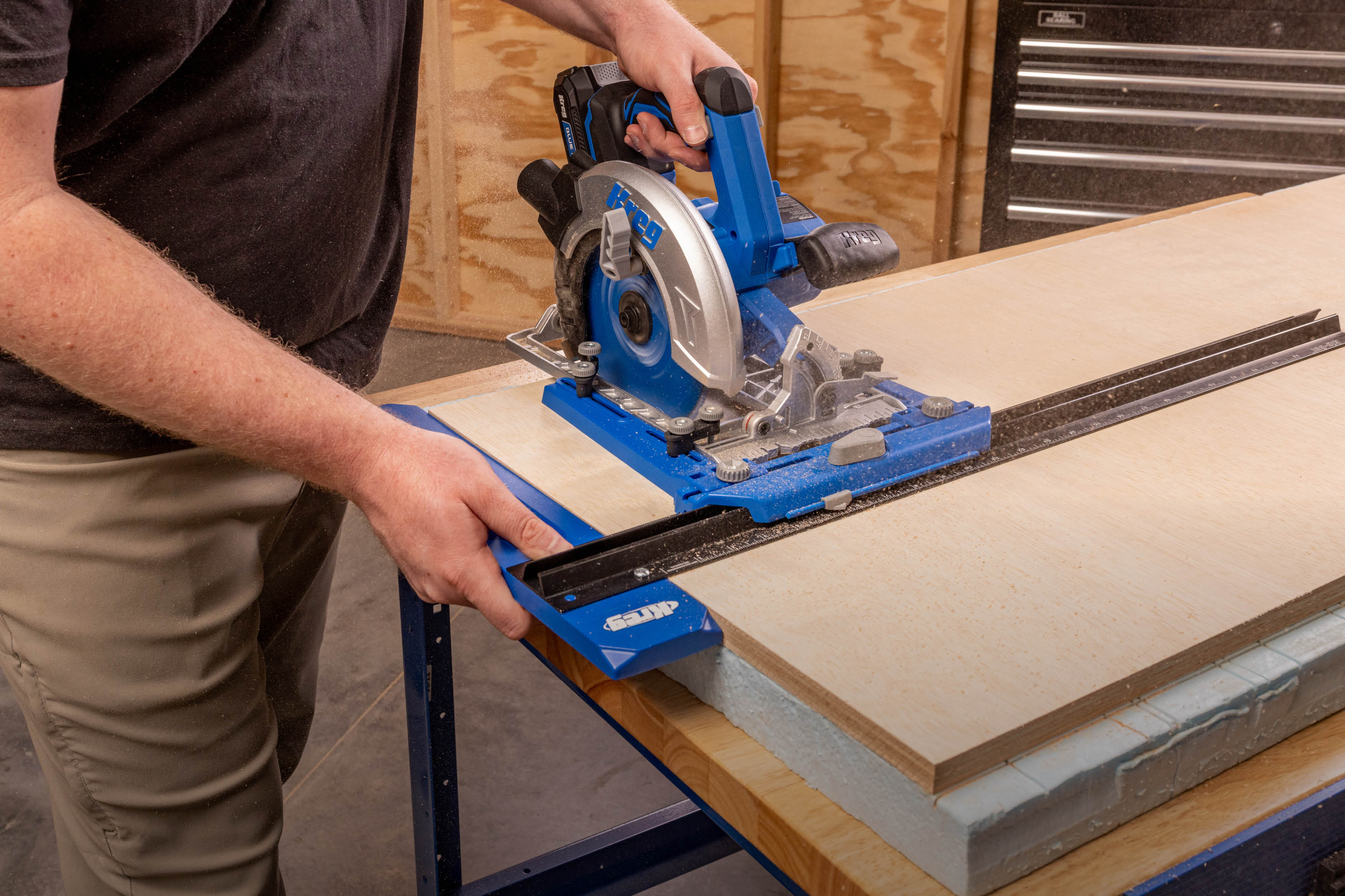 Image of a man cutting a piece of plywood with a Kreg circular saw and Rip-Cut guide