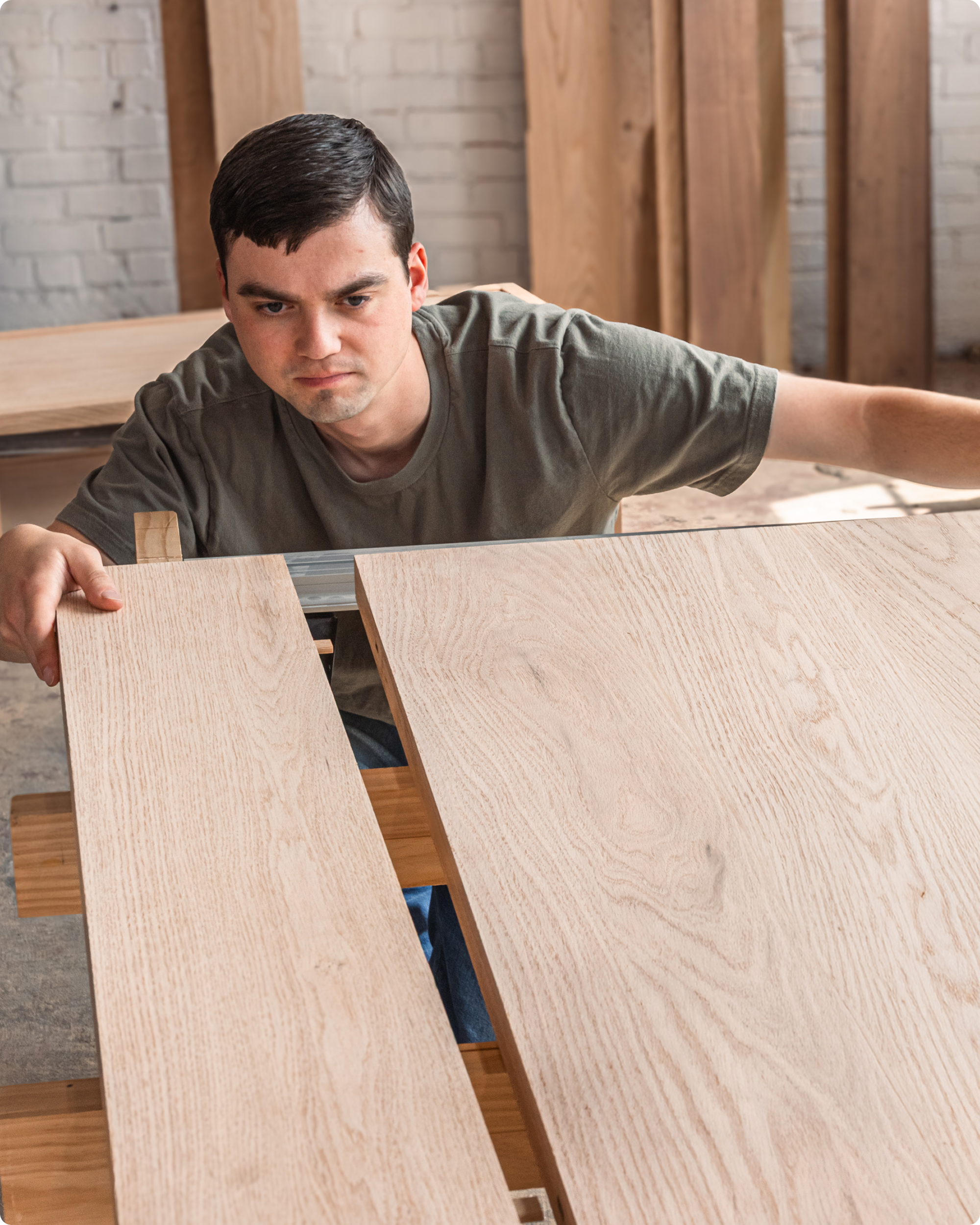 A man squatting near his woodworking project, lining up his mortise and tenon joinery. Image for Hidden Joinery callout